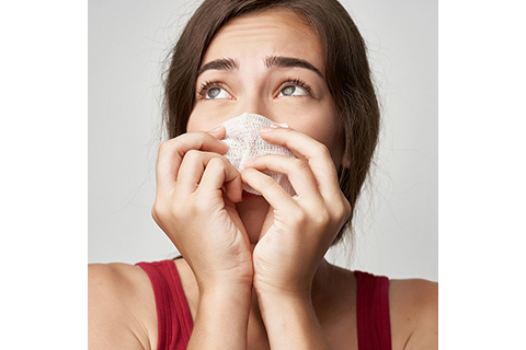 a woman wiping her nose with tissue paper